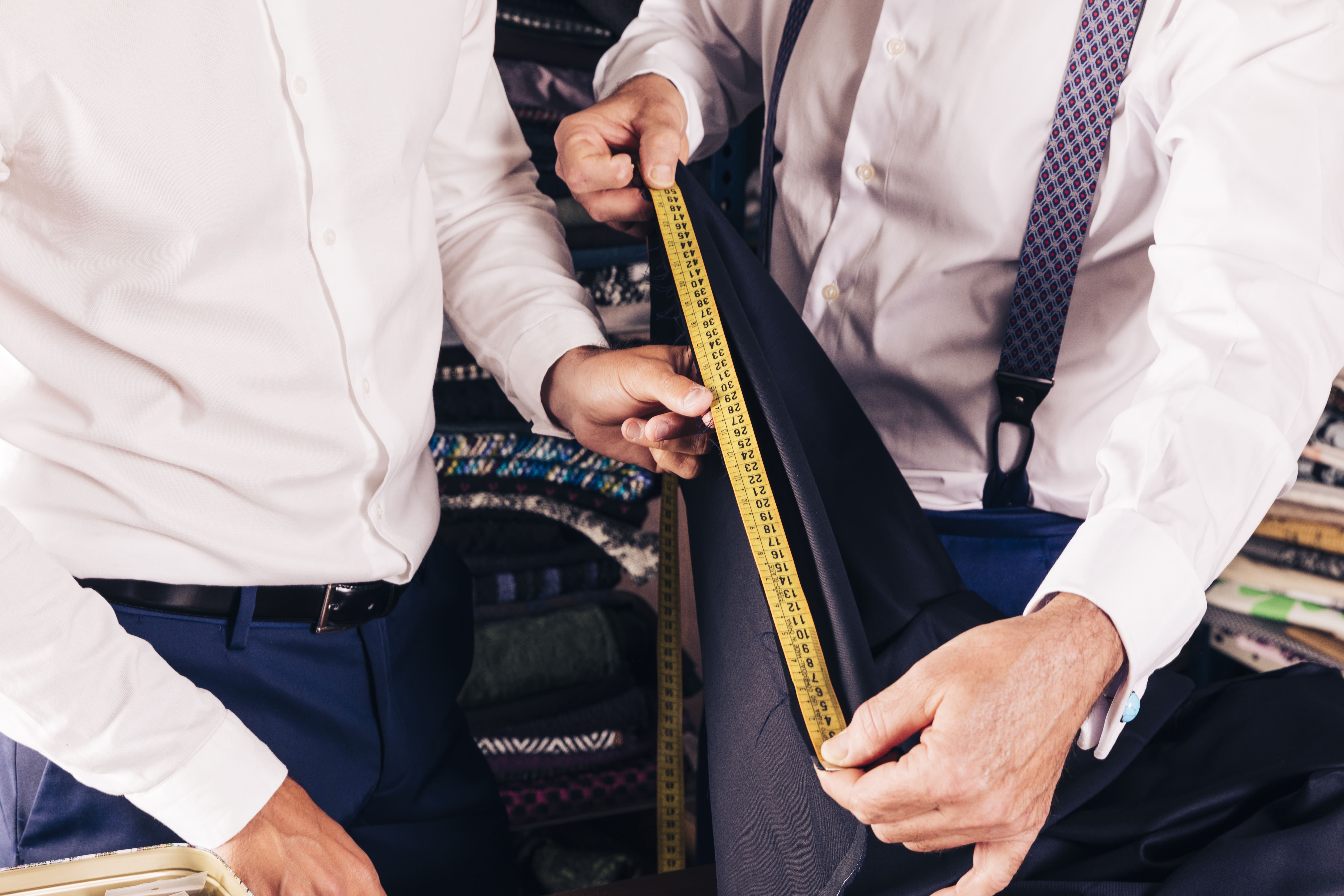 senior male tailor measuring fabric with measure table