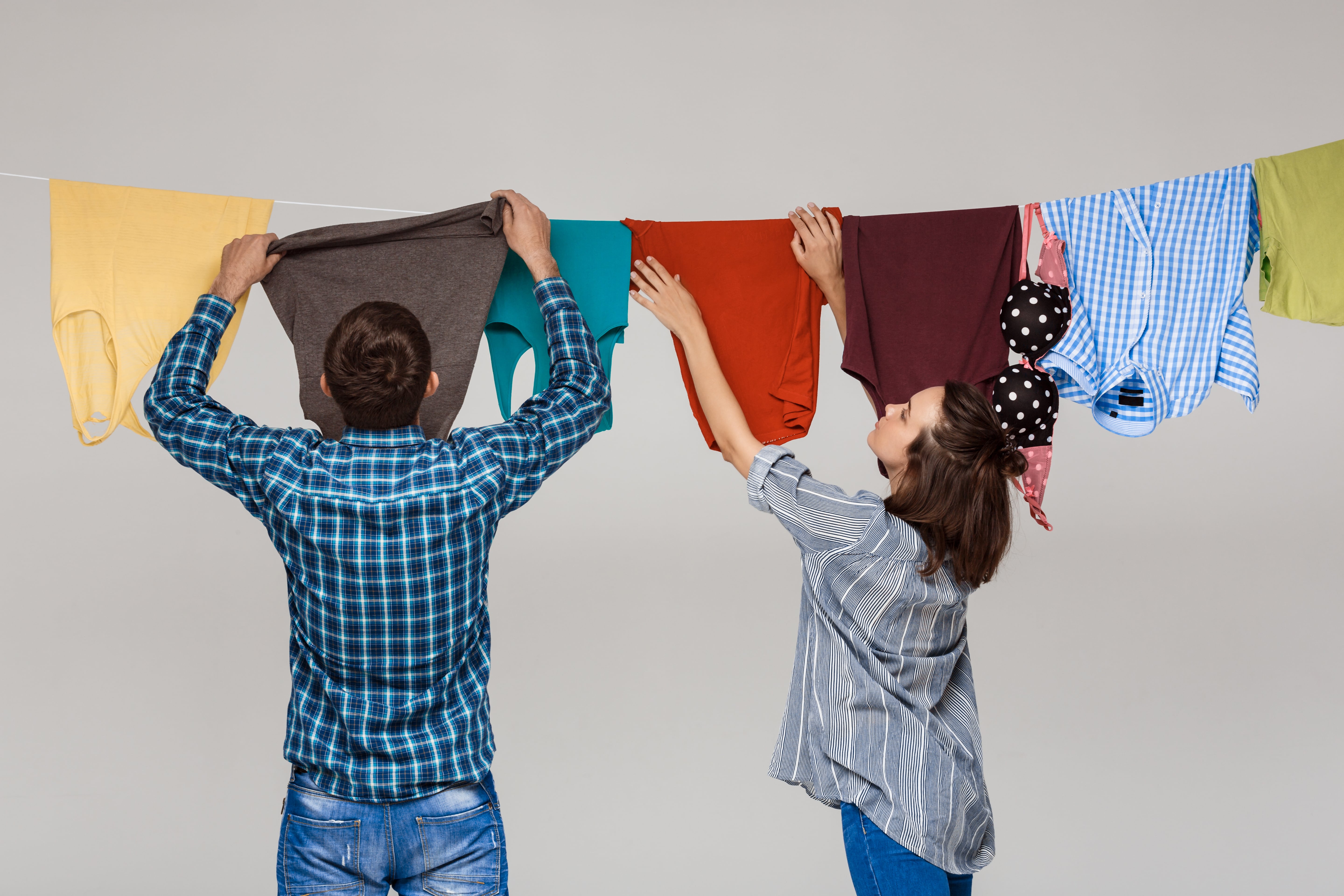 Young beautiful couple hang dry clothes on racks