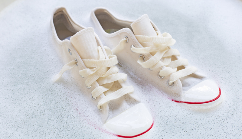 White Canvas Sneakers Soaking in Soapy Water, Highlighting the Deep Cleaning Process Offered by ByNext