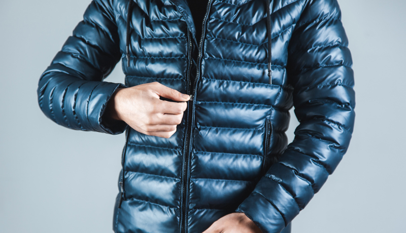 Close-up of Man Zipping a Puffer Jacket, Posing the Question of Home Washing and Care for Outerwear