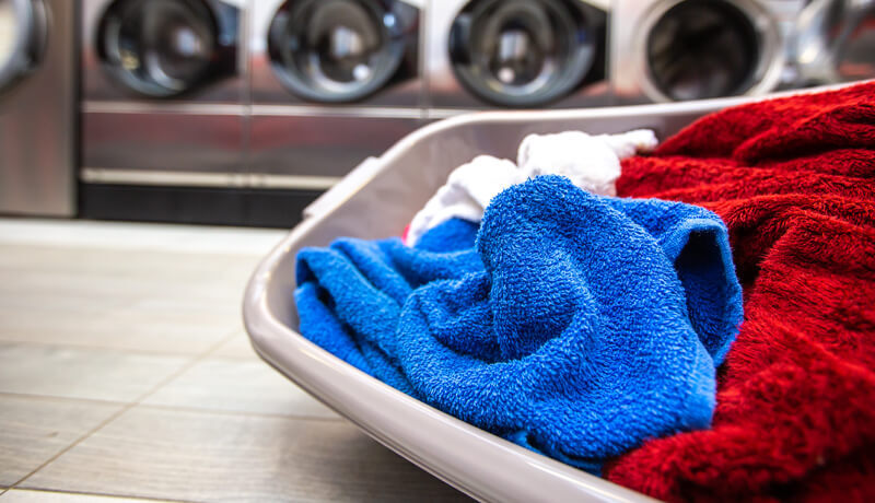 Close-up of a laundry basket with vibrant blue and red clothes in a professional facility, representing 2026 NYC laundry pickup trends and smart service solutions
