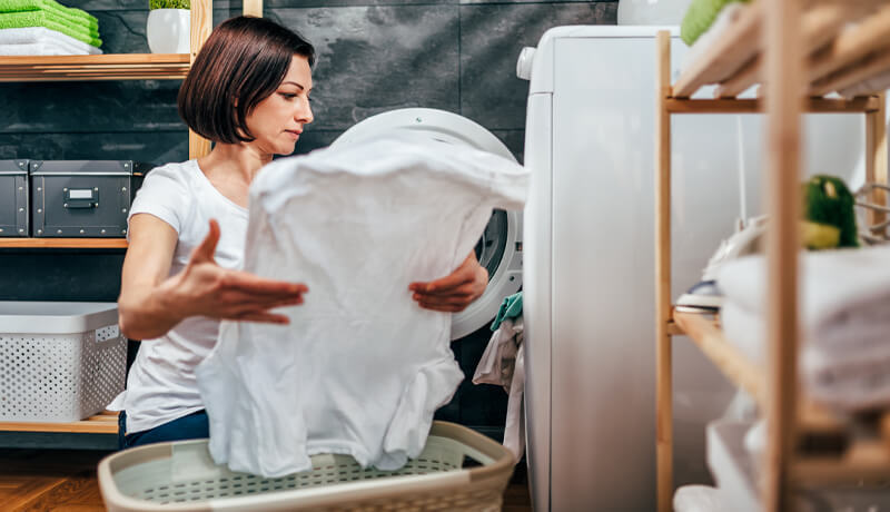 A close-up of a hand using the ByNext mobile app to schedule a laundry pickup, showing the user-friendly interface for selecting wash-and-fold and dry cleaning services.