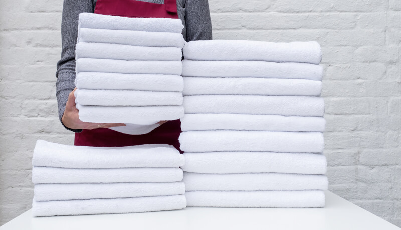 A row of high-capacity industrial washing machines in a modern urban facility, illustrating the infrastructure needed to combat rising utility costs and high demand in dense cities.